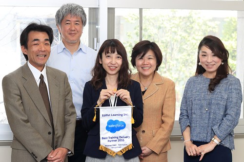 「Best Training Delivery Partner 2016」受賞記念のバナーと 弊社Salesforceトレーナー 尾谷昌也・荒木達也・鈴木さおり、 セールスフォース・ドットコム 杉山真理子様・麻生良子様（写真左より）